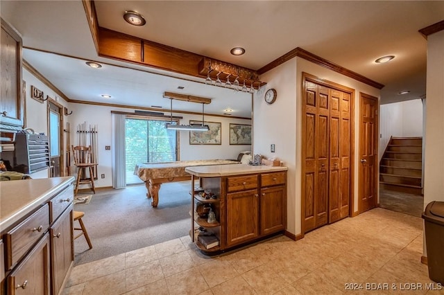 kitchen featuring light carpet, baseboards, brown cabinetry, light countertops, and crown molding