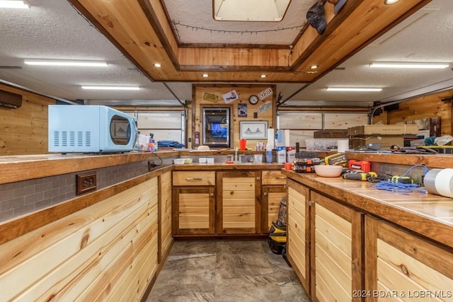 kitchen featuring a textured ceiling and wood walls