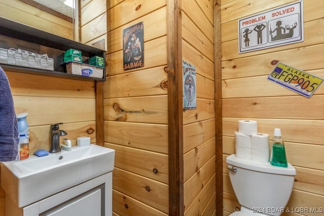 bathroom featuring vanity, toilet, and wooden walls