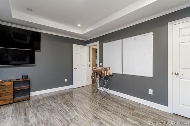 bedroom featuring wood-type flooring, crown molding, and a tray ceiling