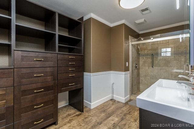 bathroom featuring hardwood / wood-style flooring, a shower with door, sink, and ornamental molding