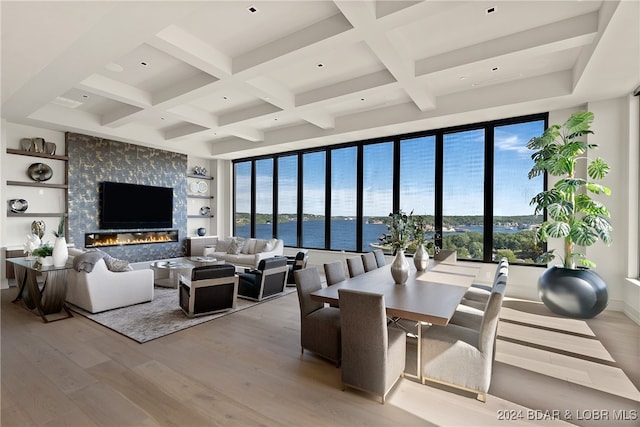 living room featuring light wood-type flooring, a large fireplace, a wealth of natural light, and coffered ceiling