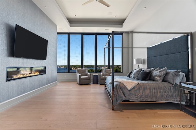 bedroom featuring a tray ceiling, light hardwood / wood-style flooring, and ceiling fan