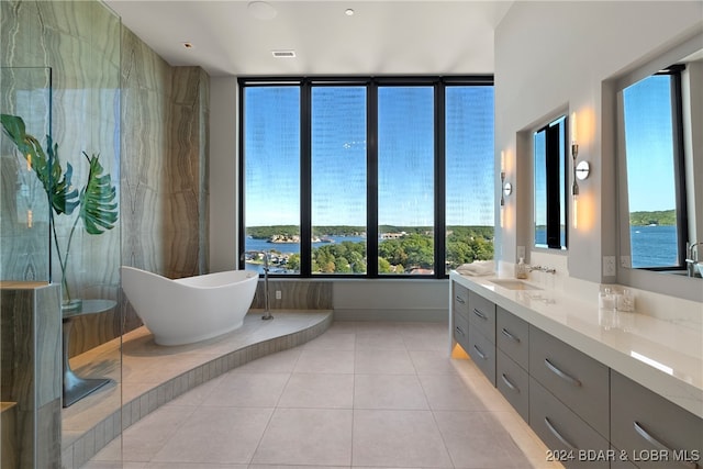 bathroom featuring vanity, a water view, a tub, and a healthy amount of sunlight