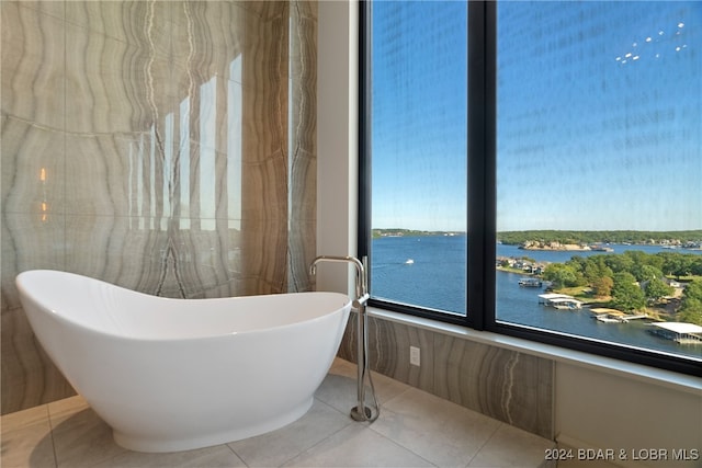 bathroom with tile patterned floors, a water view, and a bath