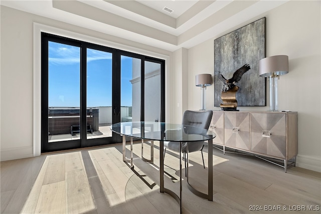 dining space with hardwood / wood-style flooring and a raised ceiling