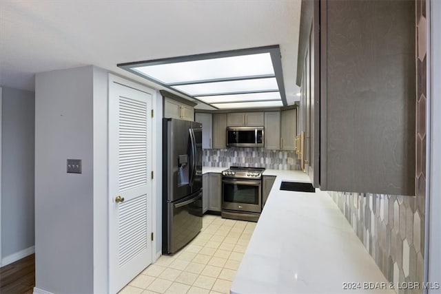 kitchen featuring tasteful backsplash, light stone countertops, light tile patterned floors, and stainless steel appliances