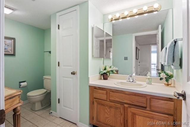 bathroom with tile patterned flooring, a textured ceiling, vanity, and toilet