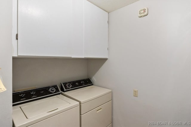 washroom with cabinets and washing machine and dryer