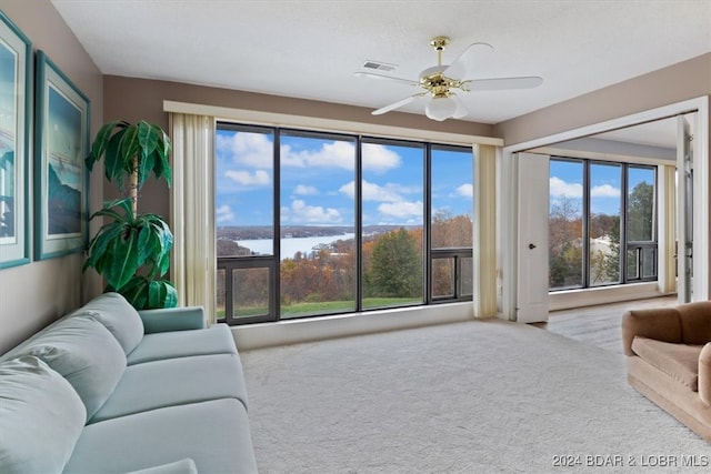 carpeted living room featuring a wealth of natural light, a water view, and ceiling fan