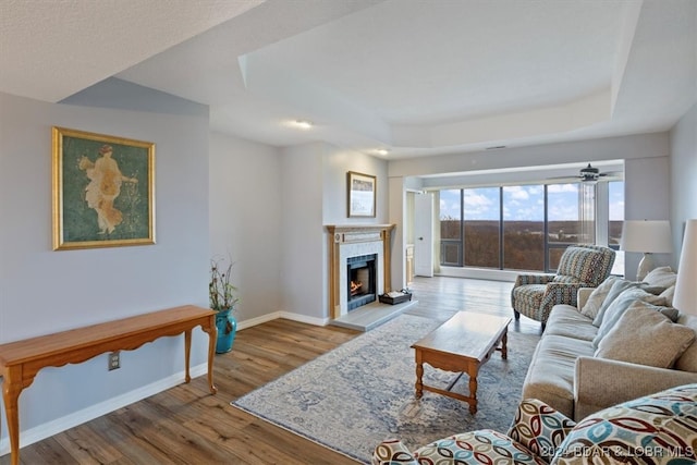 living room featuring ceiling fan, light hardwood / wood-style floors, and a tile fireplace