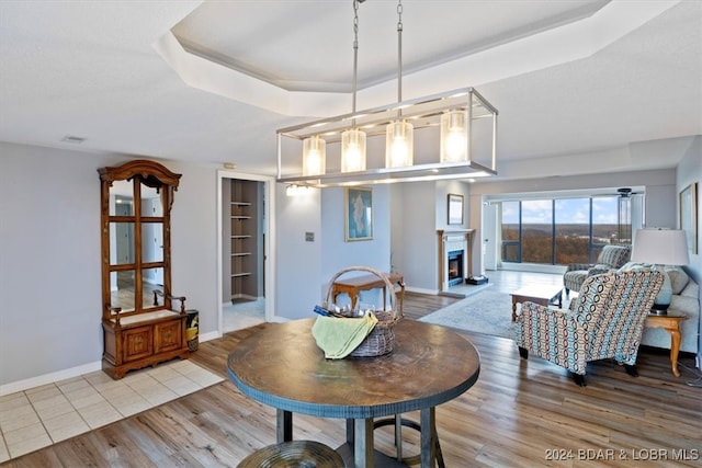 dining space featuring a raised ceiling, light hardwood / wood-style flooring, and built in shelves