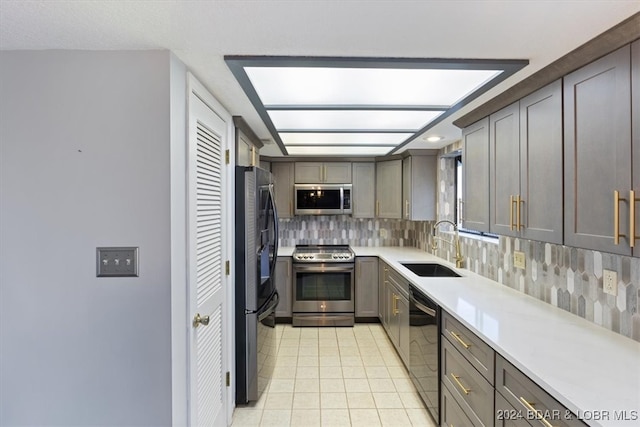 kitchen with backsplash, sink, light tile patterned floors, and stainless steel appliances