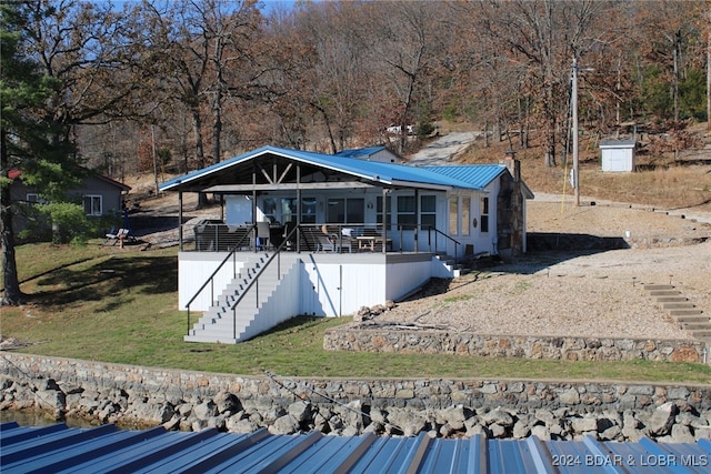 rear view of property featuring a lawn, a sunroom, and a wooden deck