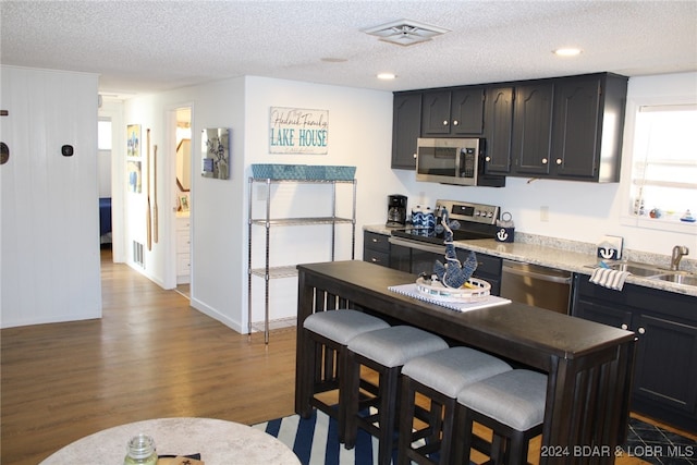 kitchen with hardwood / wood-style floors, stainless steel appliances, and a textured ceiling