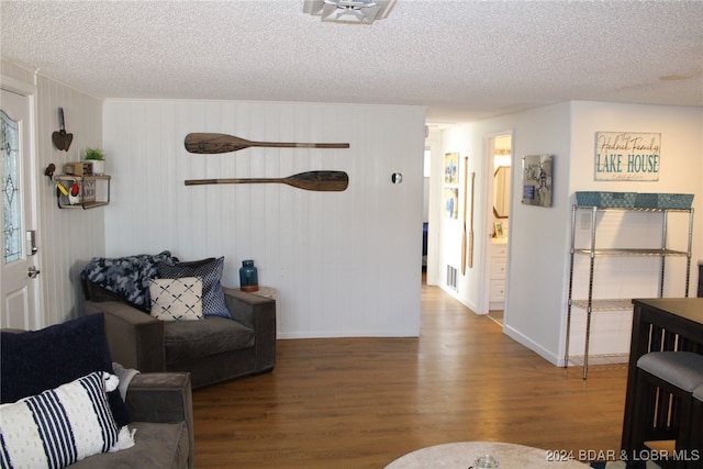 living room featuring wood-type flooring, a textured ceiling, and wood walls