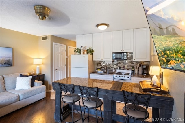 kitchen with white cabinetry, ceiling fan, dark hardwood / wood-style flooring, backsplash, and white appliances