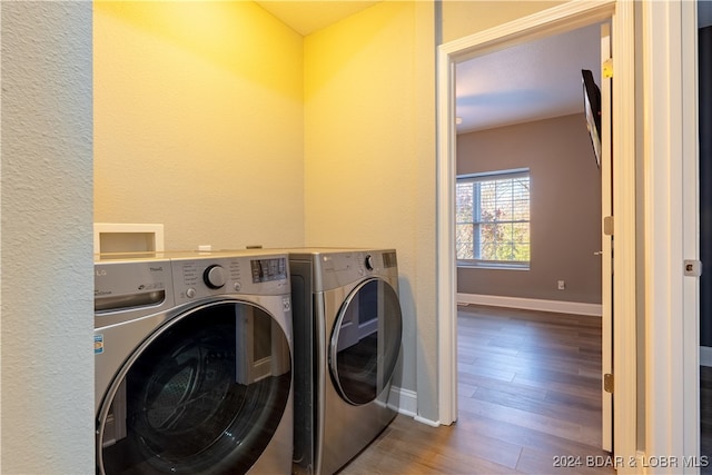 clothes washing area featuring wood-type flooring and washing machine and dryer