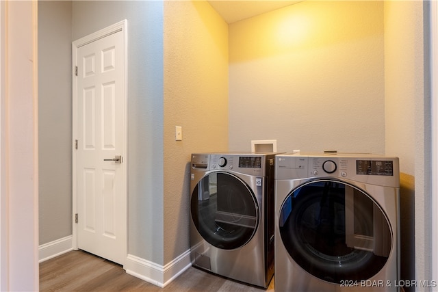 clothes washing area featuring washing machine and dryer and light wood-type flooring