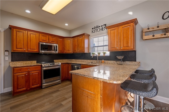 kitchen featuring kitchen peninsula, light stone counters, dark hardwood / wood-style floors, and appliances with stainless steel finishes