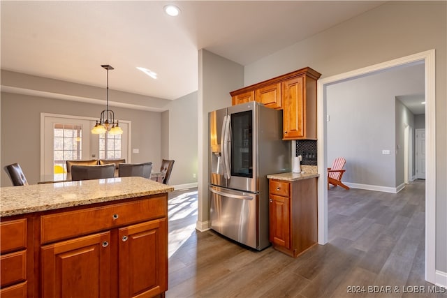 kitchen with stainless steel fridge with ice dispenser, dark hardwood / wood-style flooring, and light stone counters