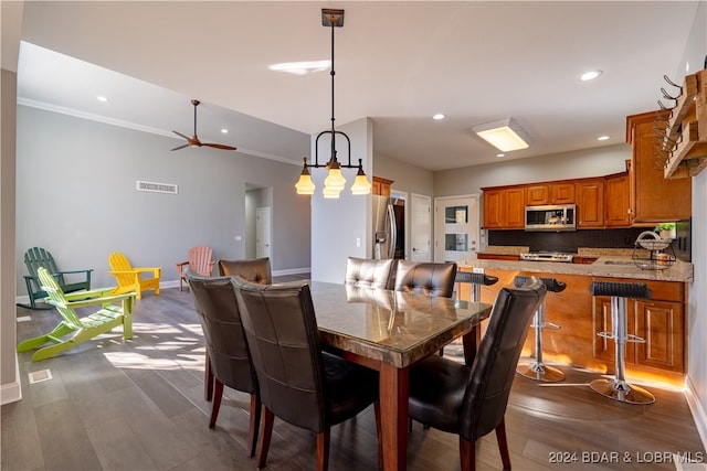 dining room with dark hardwood / wood-style floors, ceiling fan, and ornamental molding