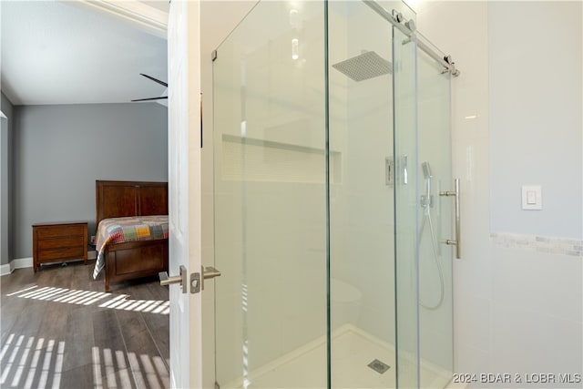 bathroom featuring hardwood / wood-style flooring, a shower with door, and tile walls