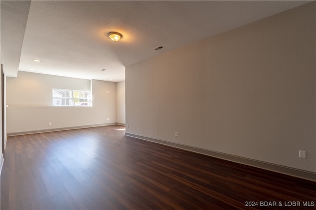 empty room with dark wood-type flooring and a textured ceiling