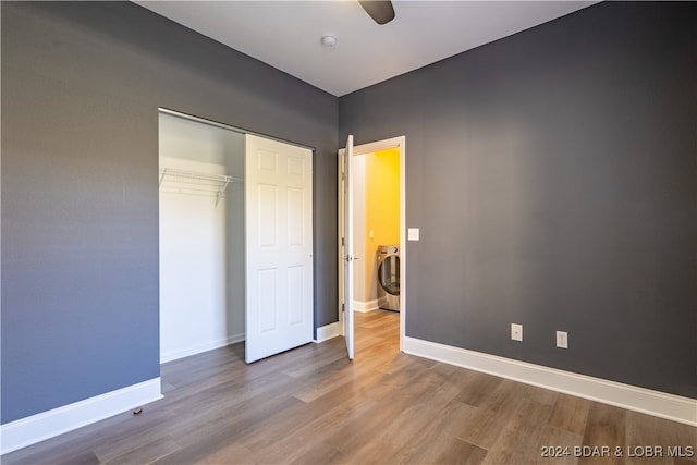 unfurnished bedroom with washer / dryer, ceiling fan, a closet, and hardwood / wood-style floors