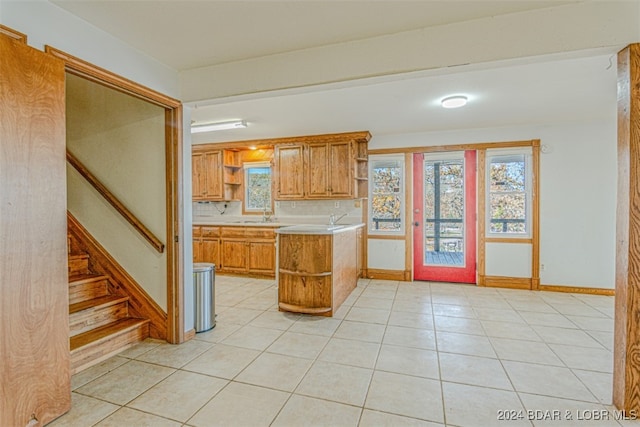 kitchen featuring tasteful backsplash, kitchen peninsula, sink, and light tile patterned flooring