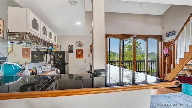 kitchen with stainless steel fridge, hardwood / wood-style flooring, and white cabinetry