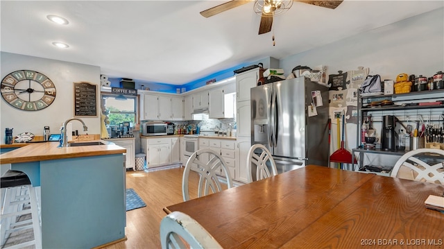 kitchen with white cabinets, sink, stainless steel appliances, and light hardwood / wood-style flooring