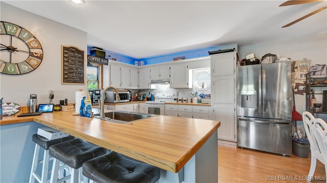 kitchen featuring kitchen peninsula, stainless steel refrigerator with ice dispenser, a breakfast bar, light hardwood / wood-style floors, and white range with electric cooktop