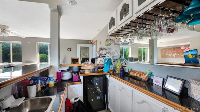 kitchen with beverage cooler, white cabinetry, and a wealth of natural light