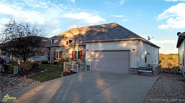 view of front facade with stone siding, an attached garage, roof with shingles, and driveway