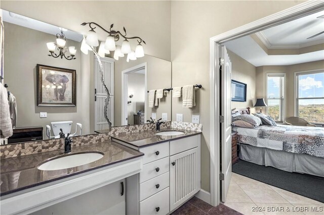 bathroom with a raised ceiling, tile patterned floors, vanity, ceiling fan with notable chandelier, and ornamental molding