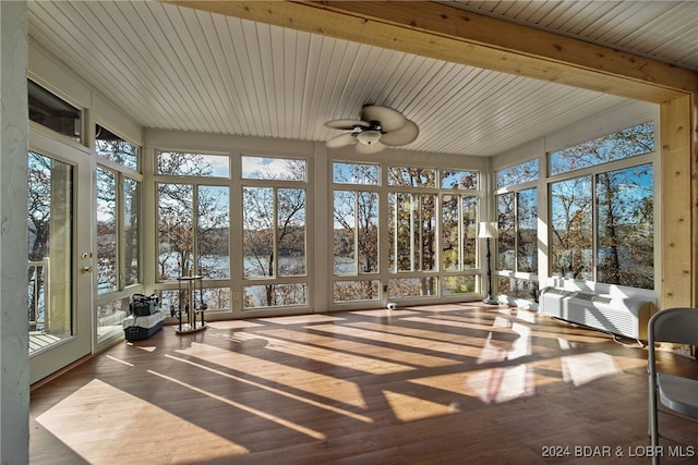 unfurnished sunroom featuring beam ceiling, a water view, and ceiling fan