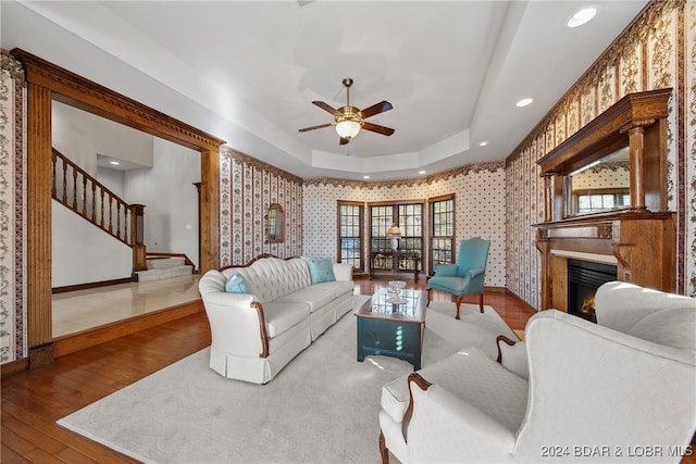 living room with hardwood / wood-style floors, a tray ceiling, and ceiling fan