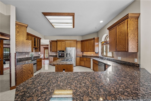 kitchen with sink, stainless steel appliances, light tile patterned floors, backsplash, and a kitchen island