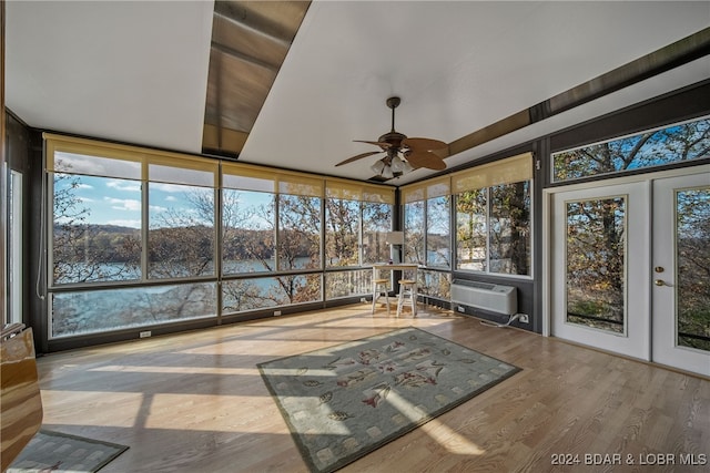 unfurnished sunroom featuring french doors, a water view, ceiling fan, and a healthy amount of sunlight