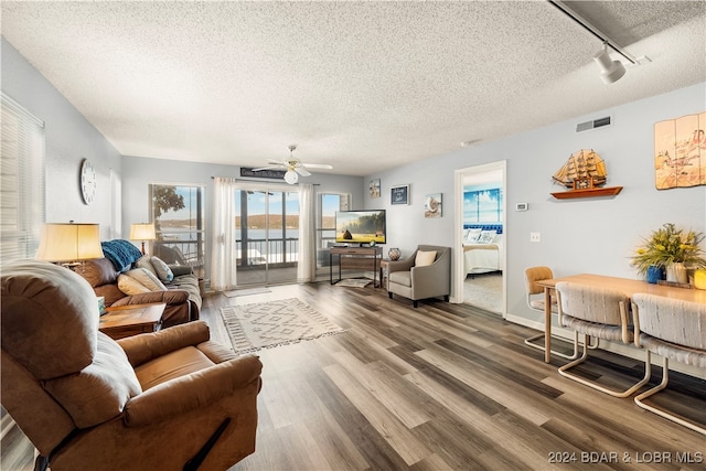 living room with rail lighting, ceiling fan, wood-type flooring, and a textured ceiling