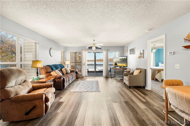 living room with ceiling fan, wood-type flooring, and a textured ceiling