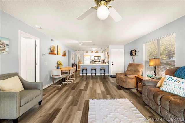 living room with a textured ceiling, dark hardwood / wood-style floors, and ceiling fan