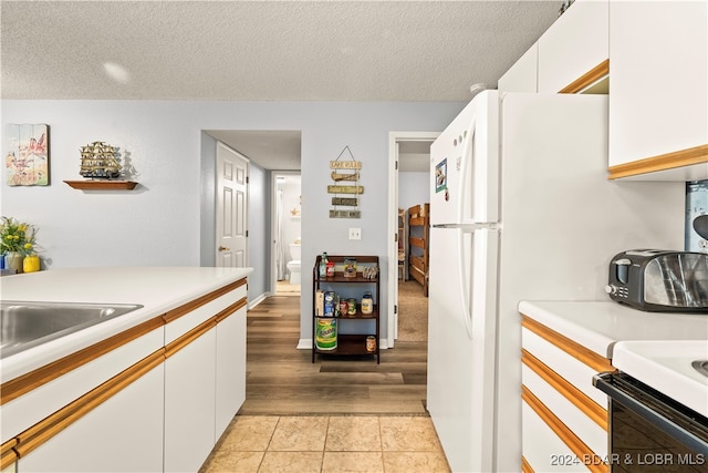 kitchen with white cabinets, a textured ceiling, and light hardwood / wood-style floors