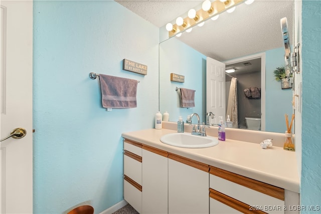 bathroom with vanity, a textured ceiling, and toilet