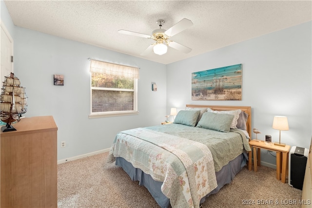 bedroom with a textured ceiling, light colored carpet, and ceiling fan