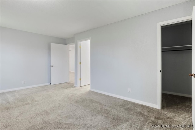 unfurnished bedroom featuring carpet floors, a closet, a spacious closet, and baseboards