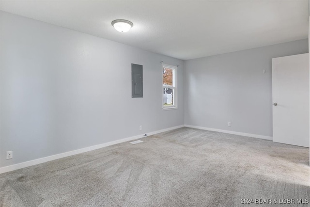 carpeted spare room featuring electric panel and baseboards