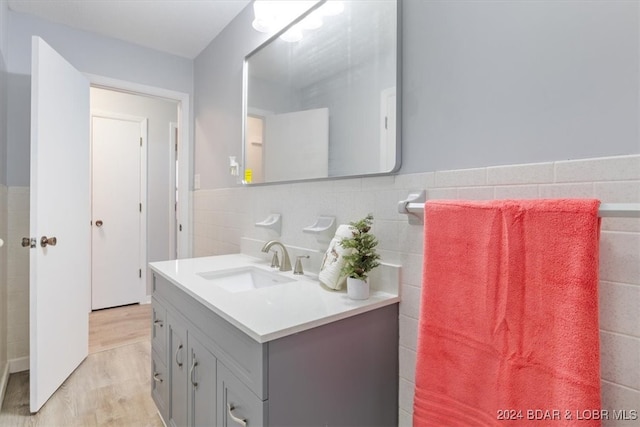 bathroom featuring wainscoting, tile walls, vanity, and wood finished floors