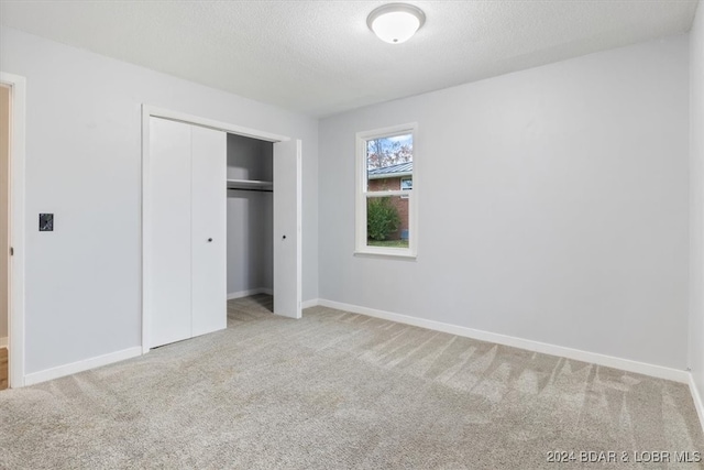 unfurnished bedroom with carpet floors, a textured ceiling, and a closet